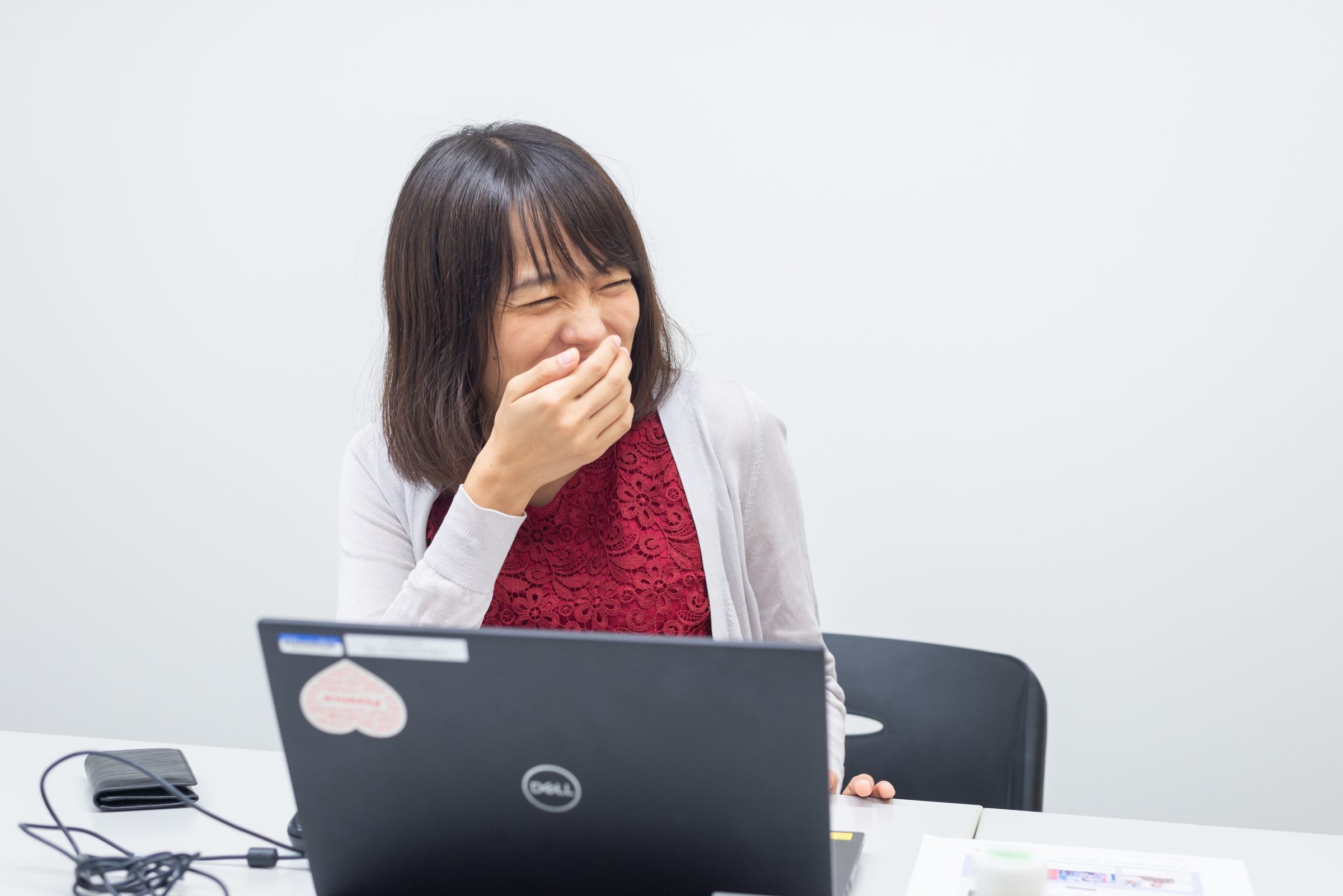 右手を口元にあて、目を細めながら笑う女性